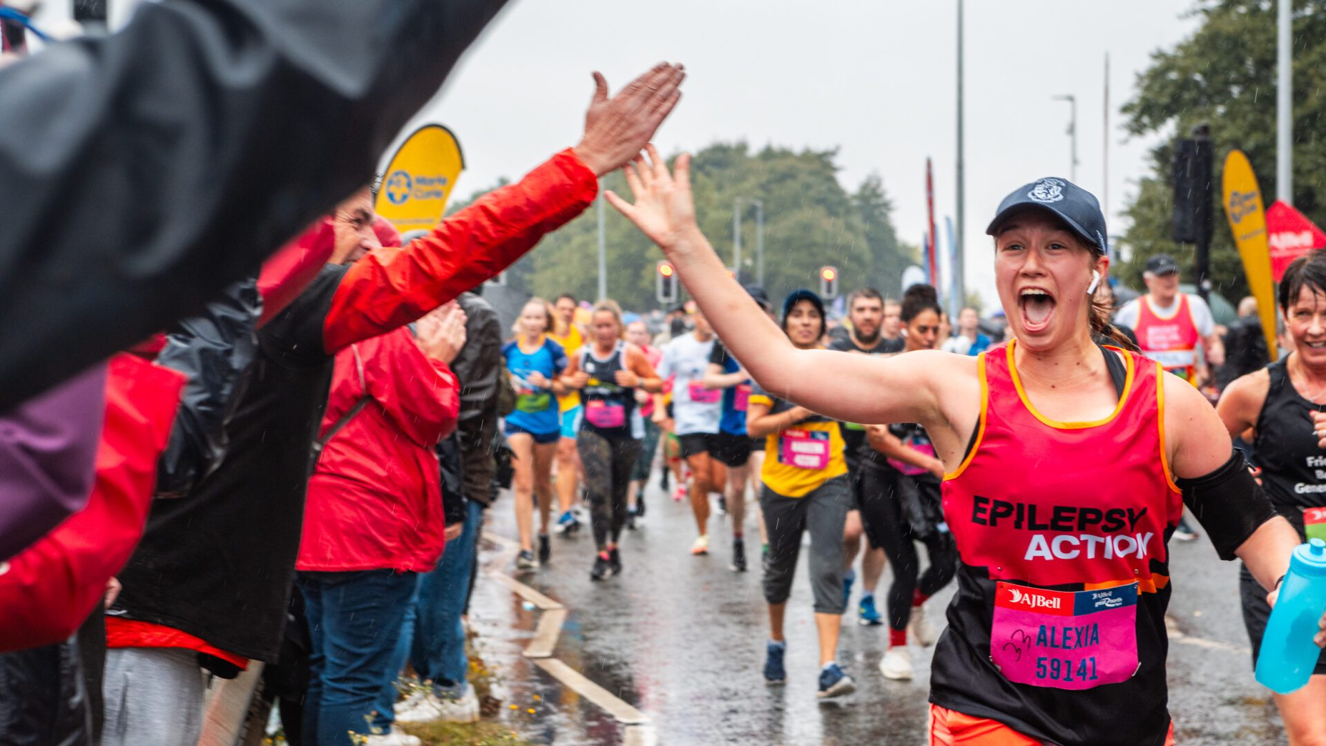 Runner waving a hi five with cheer team in the Great North Run 2024