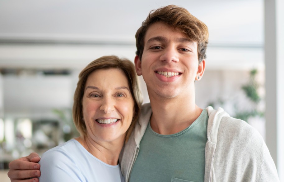 mum and young adult son embracing and facing the camera