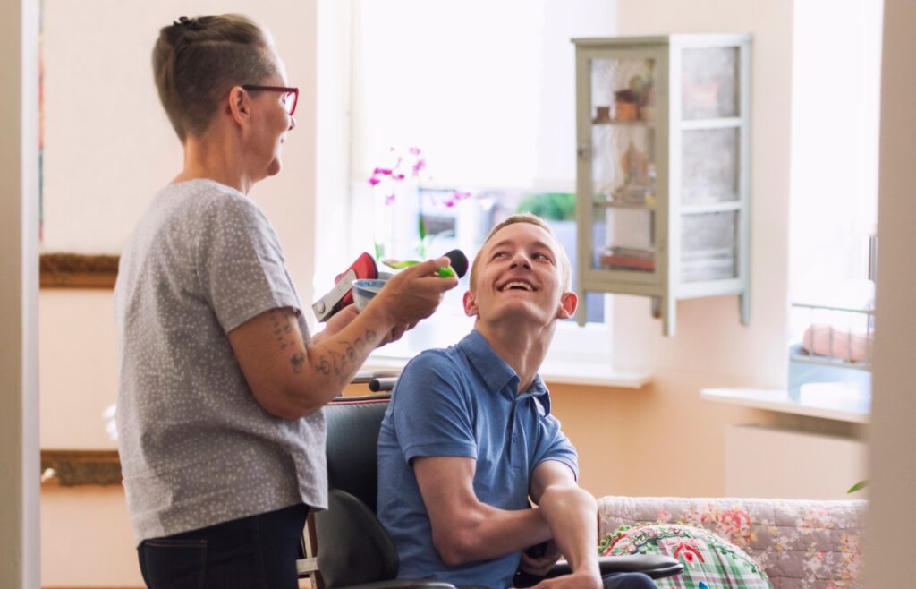 a nurse holding medicines out for a young man in a wheelchair