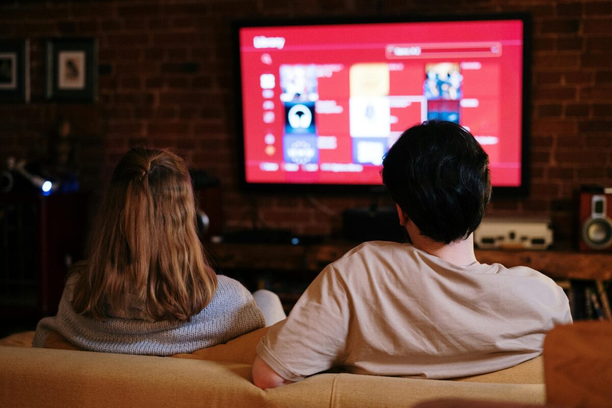 Two people sitting on a sofa watching TV