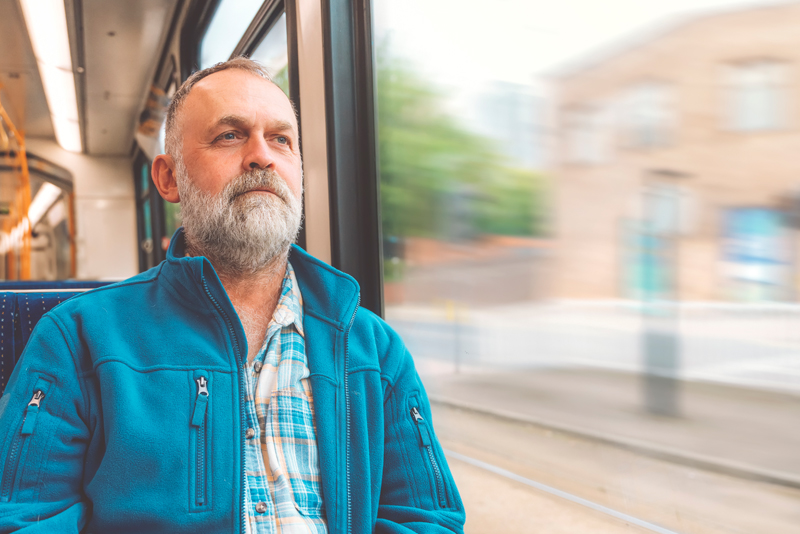 A man using sat on a bus facing forward as the bus moves