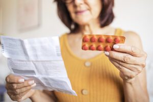 Close up of a woman checking patient information leaflet for her medicine