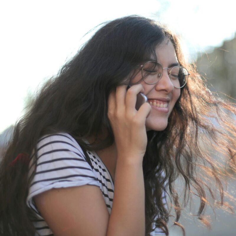 A woman with long hair talking to someone on the phone.