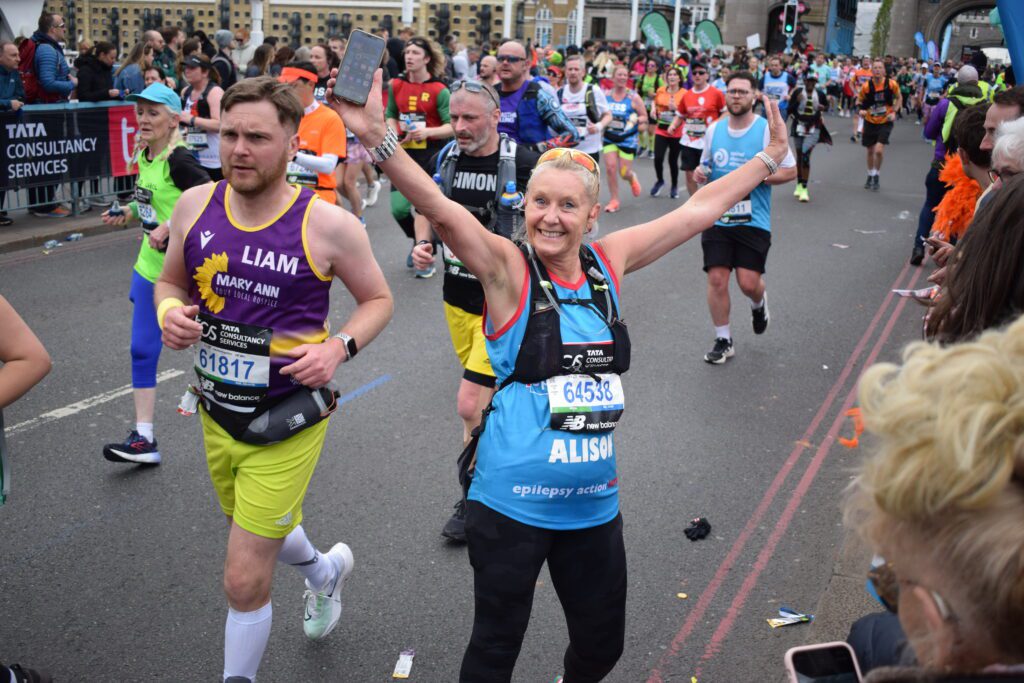 London Marathon 2026 - A female Epilepsy Action team member raised both hands up happily at Tower Bridge when she met the cheering team.