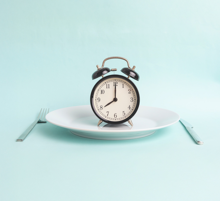 Alarm clock on dinner plate to represent fasting