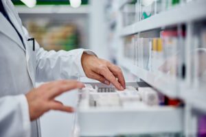 Side view of pharmacist's hands, searching for medication from the drawer.