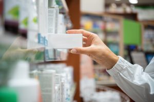 Pharmacist picking medicine box from pharmacy shelf