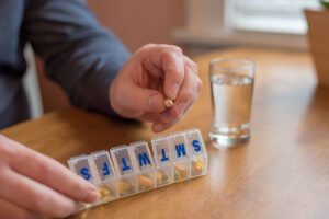 Man taking daily medications from pill box